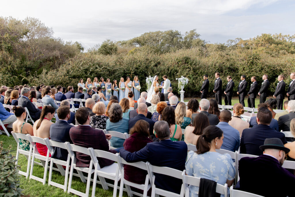 Wide shot of outdoor ceremony space as guests sit and observe the marriage of the bride and groom, in Raleigh, NC.